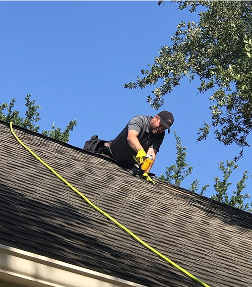 Brandon nailing on new shingles on a roof in Austin, Texas